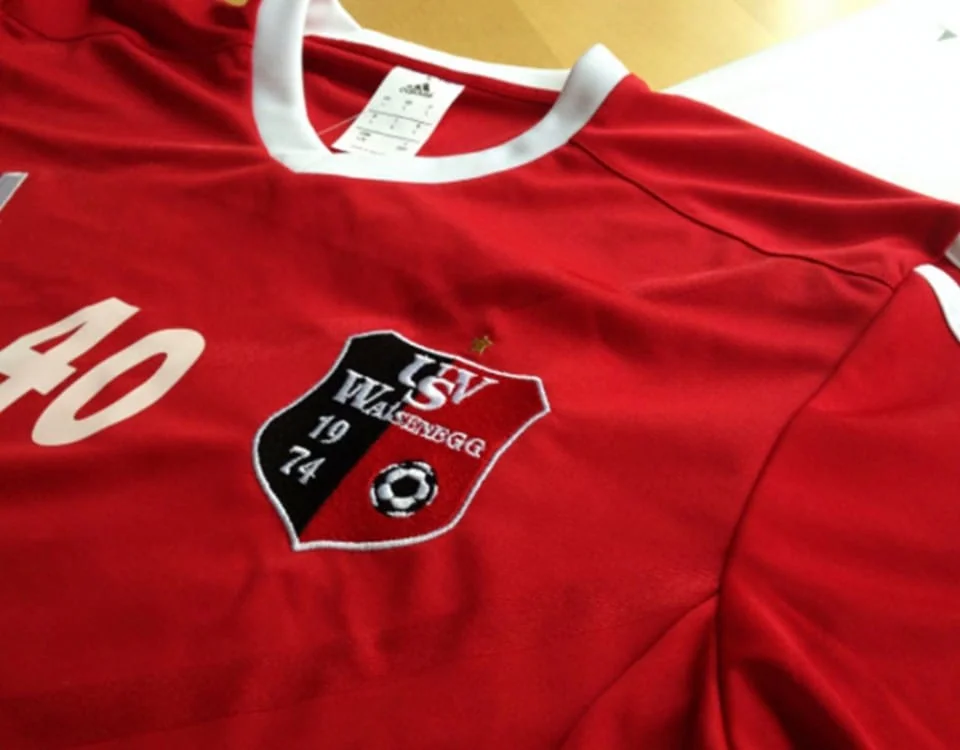 Rotes Fußballtrikot mit gesticktem Vereinswappen