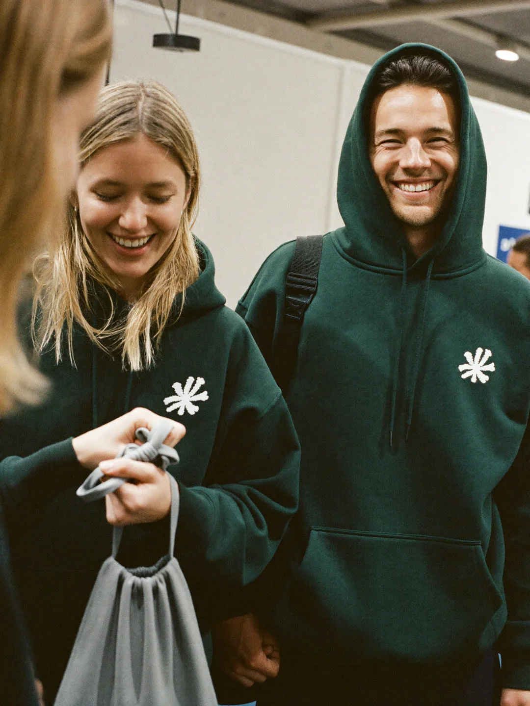 Zwei Kolleginnen und Kollegen in grünen Hoodies mit gesticktem Emblem am Messestand